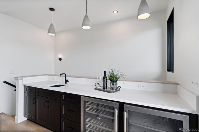 bar featuring sink, decorative light fixtures, and beverage cooler