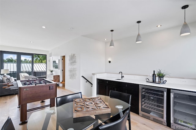 kitchen with wine cooler, hanging light fixtures, and light wood-type flooring