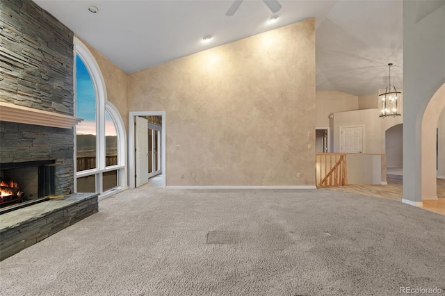 265 Ox Yoke Way, Monument, CO 80132 - unfurnished living room featuring high vaulted ceiling, carpet, arched walkways, a fireplace, and a ceiling fan