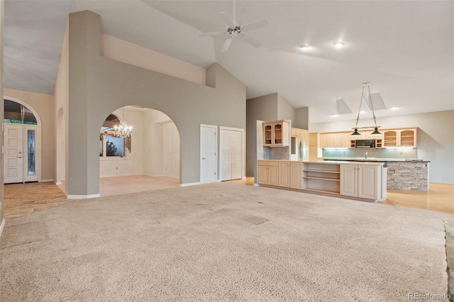 265 Ox Yoke Way, Monument, CO 80132 - unfurnished living room featuring high vaulted ceiling, arched walkways, light colored carpet, ceiling fan, and baseboards