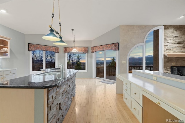 265 Ox Yoke Way, Monument, CO 80132 - kitchen featuring a sink, dark stone counters, light wood-type flooring, white cabinets, and hanging light fixtures