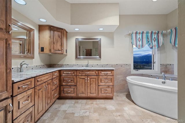 265 Ox Yoke Way, Monument, CO 80132 - full bathroom featuring double vanity, recessed lighting, a soaking tub, stone finish floors, and tile walls