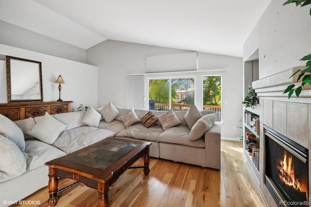 living room with light hardwood / wood-style flooring, vaulted ceiling, and a fireplace