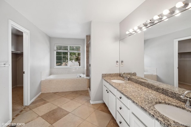 full bathroom with a spacious closet, a shower stall, a sink, and a bath