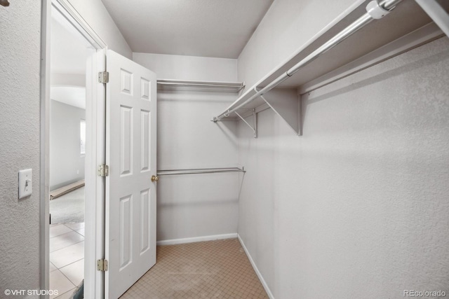 walk in closet with light tile patterned floors