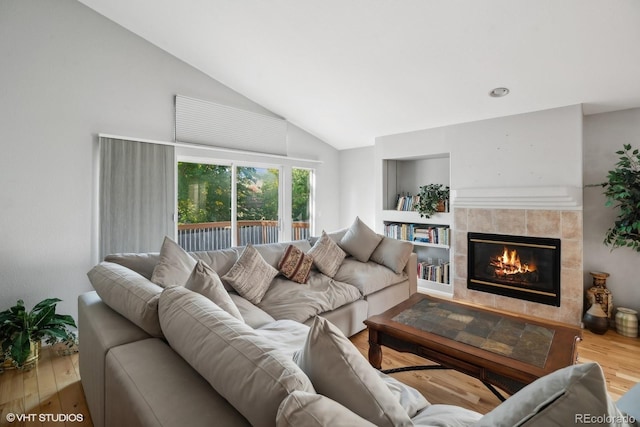 living room with a tiled fireplace, hardwood / wood-style flooring, and high vaulted ceiling