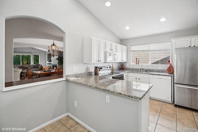 kitchen with lofted ceiling, appliances with stainless steel finishes, kitchen peninsula, and white cabinetry