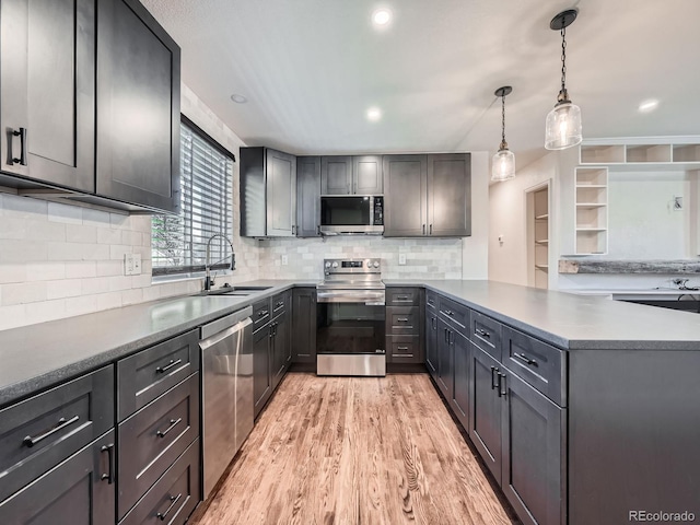 kitchen featuring sink, stainless steel appliances, light hardwood / wood-style flooring, kitchen peninsula, and pendant lighting