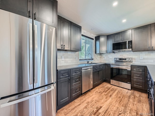 kitchen with decorative backsplash, sink, stainless steel appliances, and light hardwood / wood-style floors