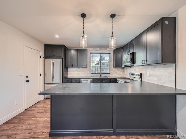 kitchen with sink, stainless steel appliances, tasteful backsplash, dark hardwood / wood-style floors, and pendant lighting