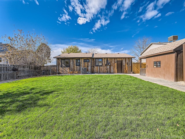 rear view of property featuring central AC and a yard