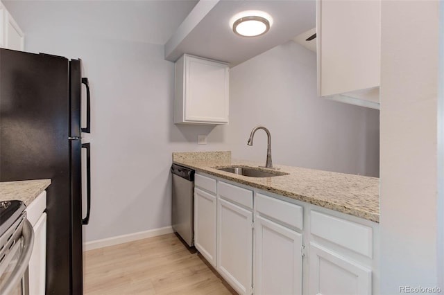 kitchen featuring appliances with stainless steel finishes, white cabinets, a sink, light stone countertops, and baseboards