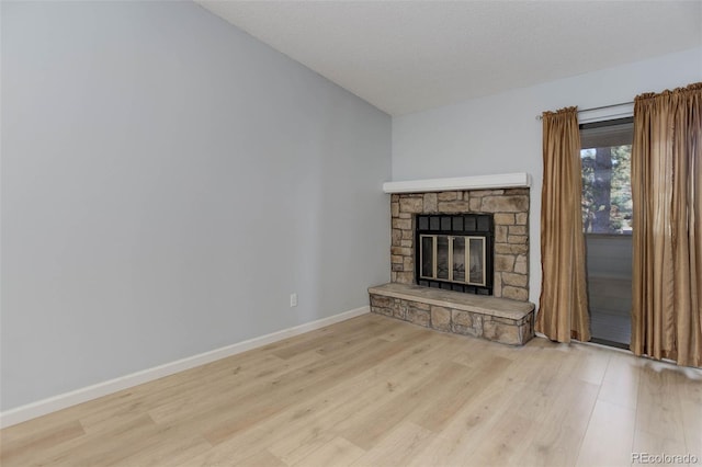 unfurnished living room with a fireplace, baseboards, and wood finished floors