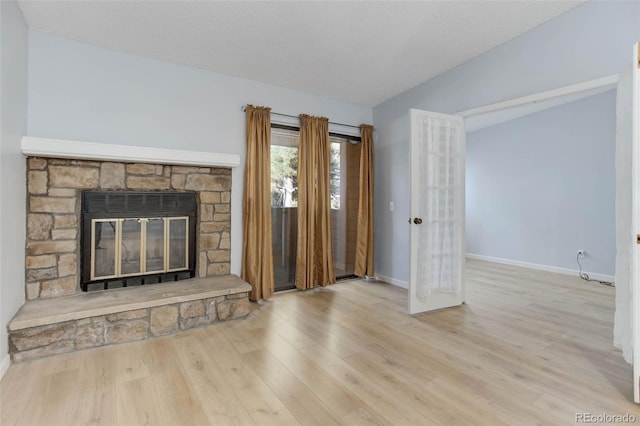 unfurnished living room featuring vaulted ceiling, a fireplace, baseboards, and wood finished floors