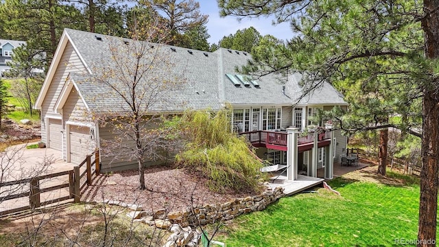 4185 Cheyenne Dr, Larkspur, CO 80118 - back of property featuring a wooden deck, concrete driveway, a shingled roof, a garage, and a lawn