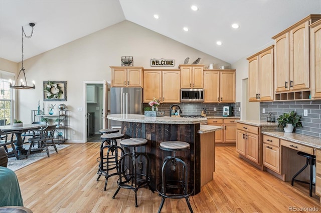 4185 Cheyenne Dr, Larkspur, CO 80118 - kitchen with appliances with stainless steel finishes, light wood-style flooring, light brown cabinetry, a kitchen bar, and high vaulted ceiling
