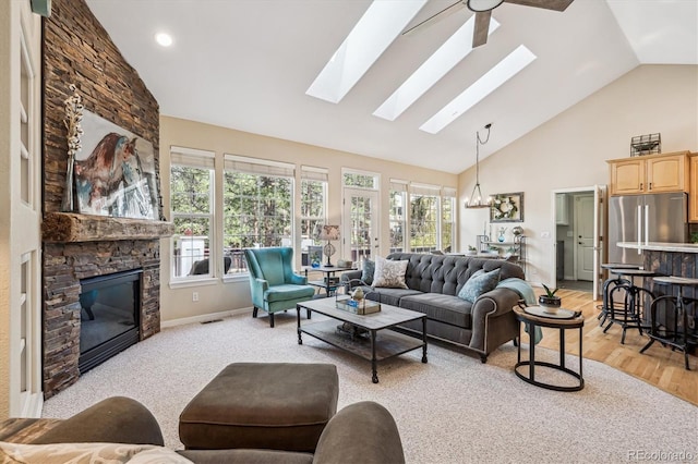 4185 Cheyenne Dr, Larkspur, CO 80118 - living area with a skylight, high vaulted ceiling, a stone fireplace, light wood-type flooring, and baseboards