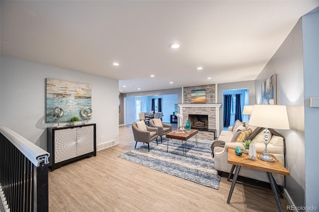 living room featuring visible vents, wood finished floors, recessed lighting, a stone fireplace, and baseboards