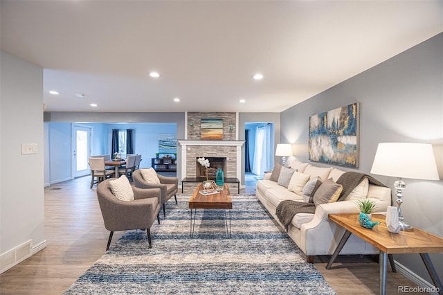 living room featuring wood finished floors, visible vents, baseboards, a fireplace, and recessed lighting