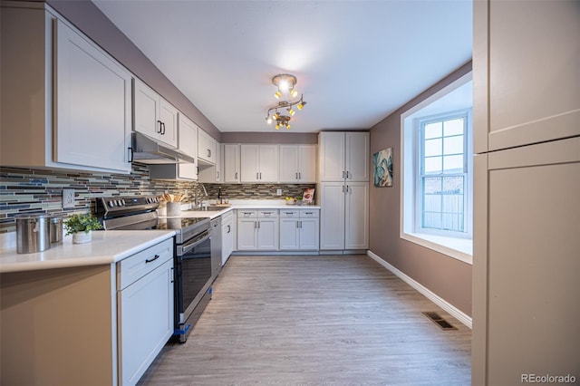 kitchen with visible vents, backsplash, under cabinet range hood, stainless steel electric stove, and a sink