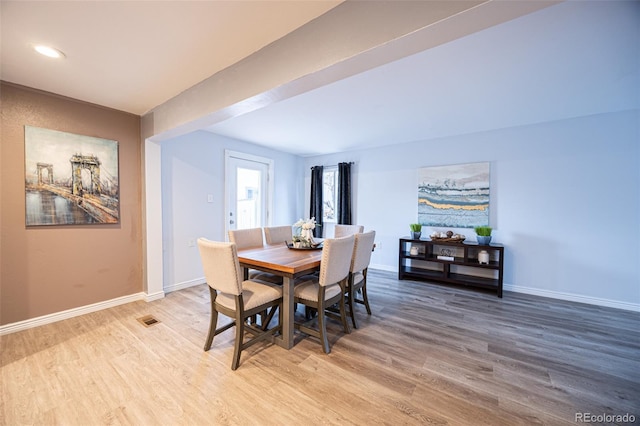 dining space with light wood-type flooring, baseboards, and visible vents