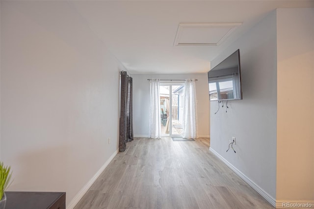 corridor with attic access, light wood-style floors, and baseboards