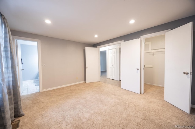 unfurnished bedroom with a spacious closet, baseboards, light carpet, recessed lighting, and a closet