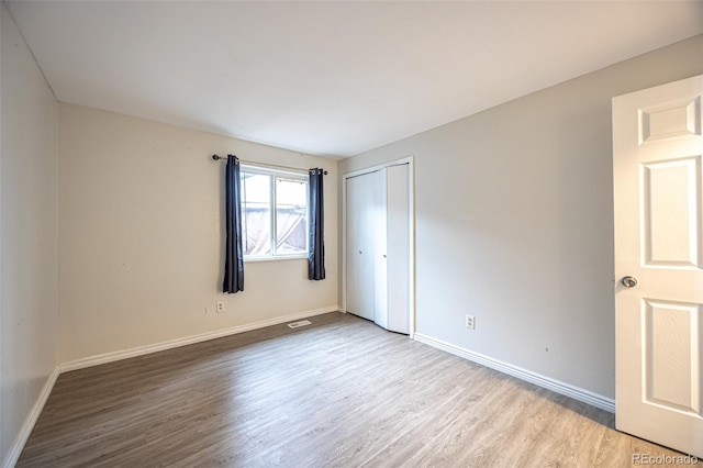 spare room with visible vents, baseboards, and wood finished floors