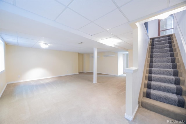 finished below grade area with a drop ceiling, light colored carpet, stairs, and baseboards