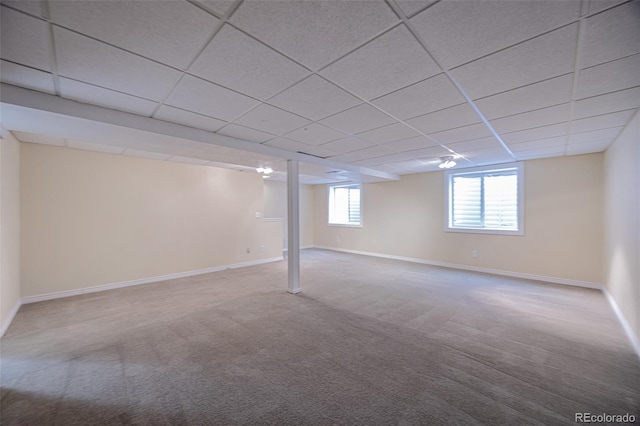 basement featuring carpet flooring, a paneled ceiling, and baseboards