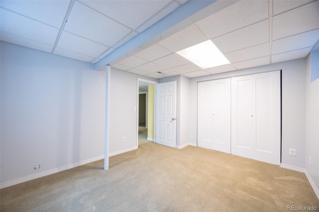 finished basement with a drop ceiling, baseboards, and carpet floors