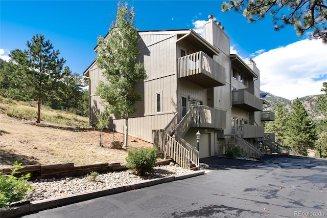 view of property featuring aphalt driveway, a garage, and stairway