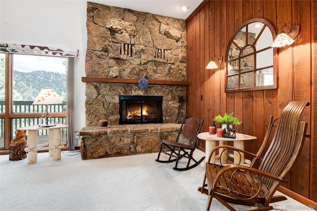 living area featuring a fireplace, wood walls, and carpet floors