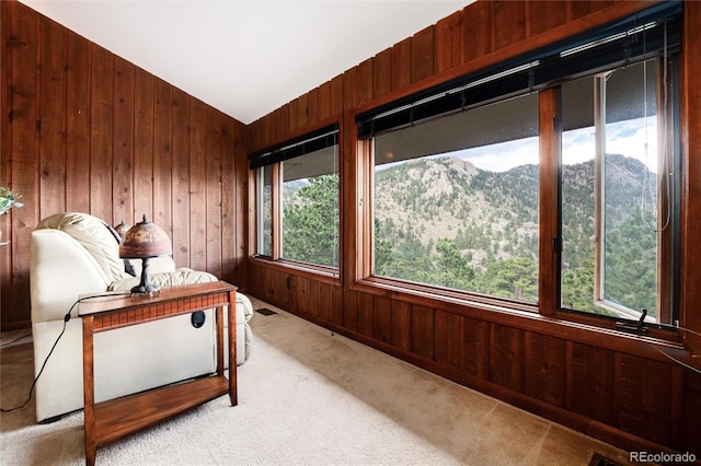 living area featuring a mountain view, light carpet, lofted ceiling, and wood walls