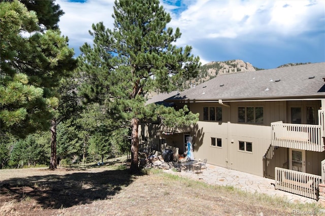 back of house featuring a balcony and roof with shingles