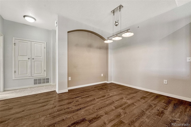 spare room featuring dark hardwood / wood-style flooring and a textured ceiling