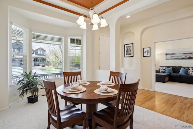 carpeted dining space featuring arched walkways, baseboards, and plenty of natural light