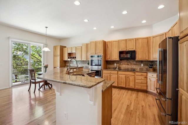 kitchen with a sink, tasteful backsplash, black appliances, and a kitchen bar
