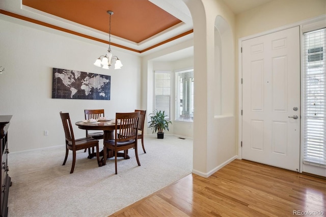 dining room featuring arched walkways, an inviting chandelier, a healthy amount of sunlight, and light wood finished floors