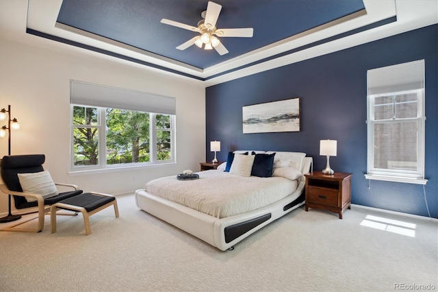 carpeted bedroom featuring baseboards, a ceiling fan, and a tray ceiling