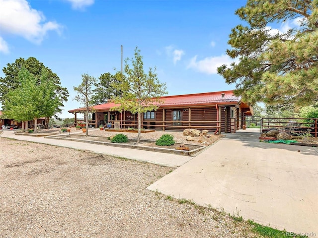 view of front of home with metal roof, an outdoor structure, an exterior structure, and log exterior