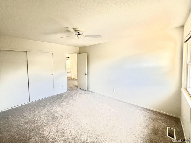 unfurnished bedroom featuring ceiling fan, carpet floors, a textured ceiling, and a closet