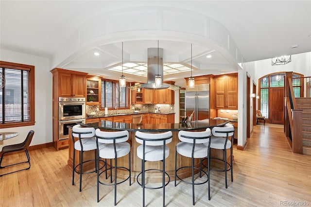 1351 S Milwaukee St, Denver, CO 80210 - kitchen with appliances with stainless steel finishes, open shelves, island exhaust hood, and brown cabinetry