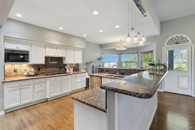 1550 Ajax St, Strasburg, CO 80136 - kitchen with black microwave, white cabinetry, light wood-style floors, backsplash, and recessed lighting
