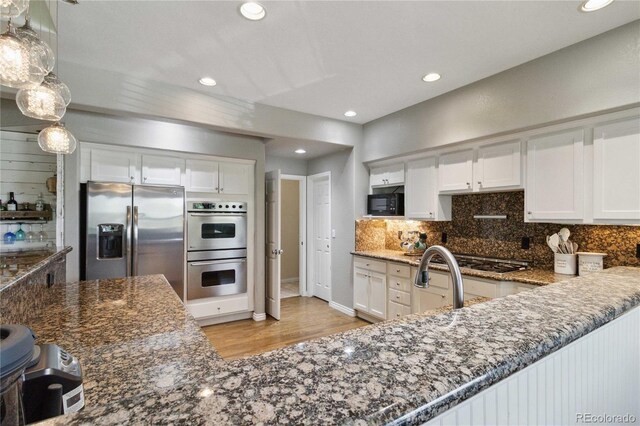 1550 Ajax St, Strasburg, CO 80136 - kitchen with appliances with stainless steel finishes, light wood-type flooring, dark stone countertops, tasteful backsplash, and white cabinetry