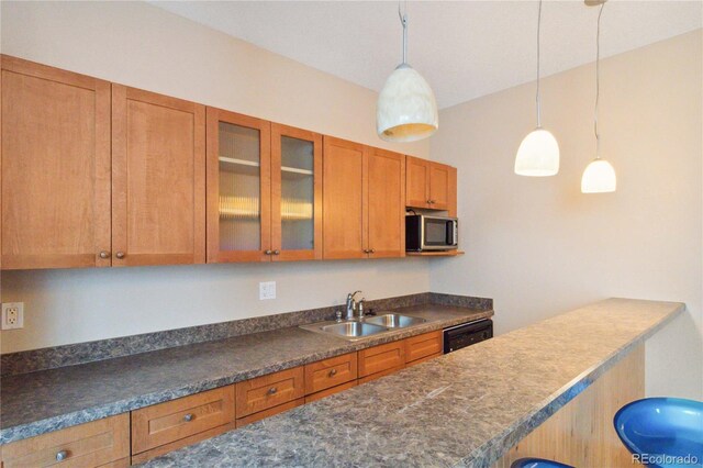 1550 Ajax St, Strasburg, CO 80136 - kitchen featuring stainless steel microwave, dark countertops, brown cabinetry, glass insert cabinets, and pendant lighting
