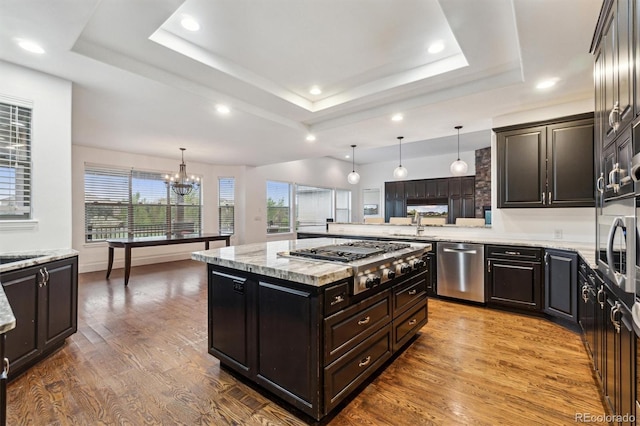 12939 Wabash Ct, Thornton, CO 80602 - kitchen with appliances with stainless steel finishes, a chandelier, a raised ceiling, wood finished floors, and recessed lighting