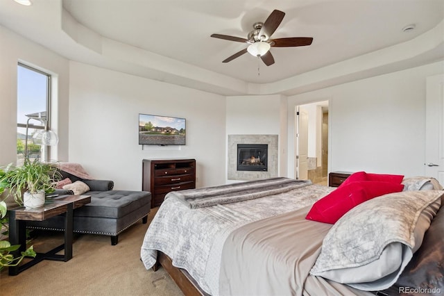 12939 Wabash Ct, Thornton, CO 80602 - bedroom with a raised ceiling, light carpet, a glass covered fireplace, and a ceiling fan