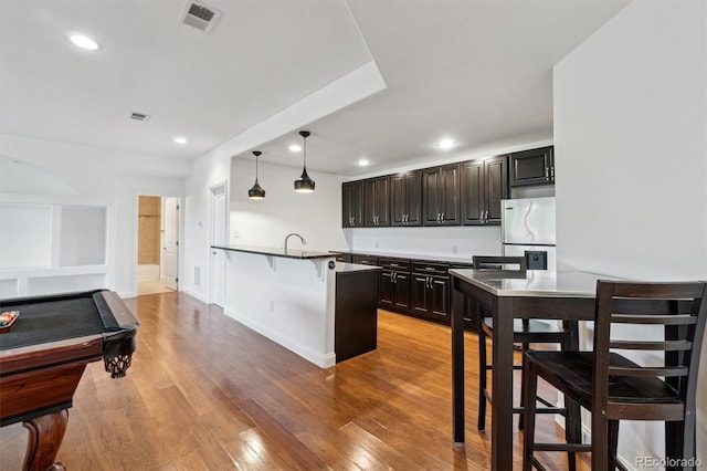 12939 Wabash Ct, Thornton, CO 80602 - kitchen with a breakfast bar area, light wood finished floors, stainless steel refrigerator, recessed lighting, and pendant lighting