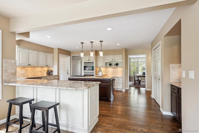 5320 S Geneva St, Englewood, CO 80111 - kitchen with a peninsula, decorative backsplash, dark wood-style flooring, decorative light fixtures, and light stone counters